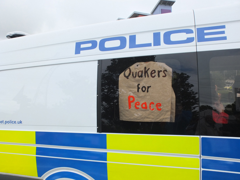 sign in police van window says Quakers for peace