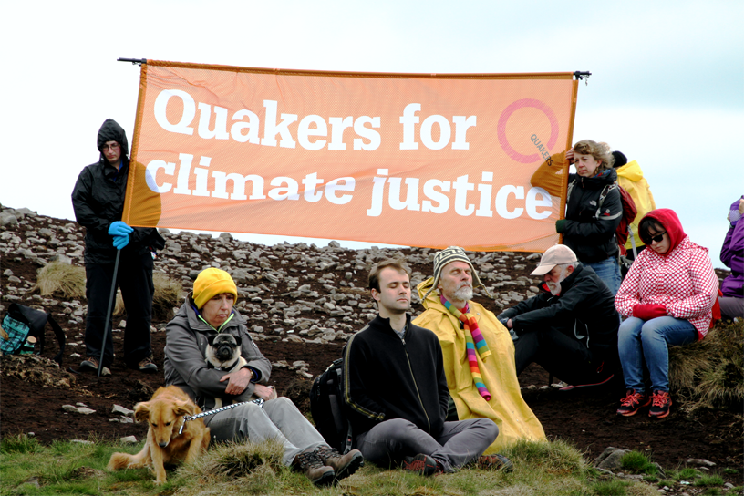 Atop Pendle Hill, activist mfw under orange Quakers for climate justice banner