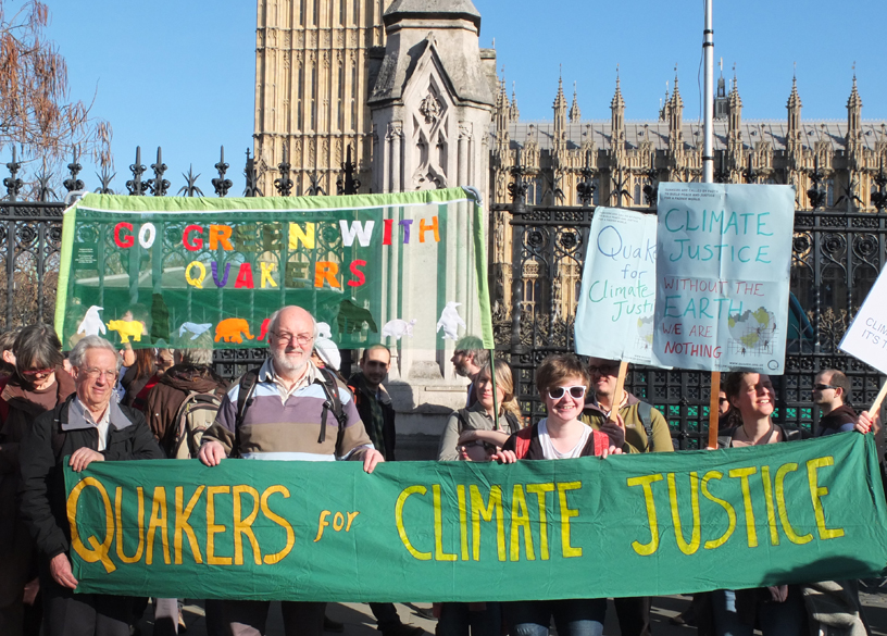 Quakers outside parliament holding green banner, says Quakers for climate justice