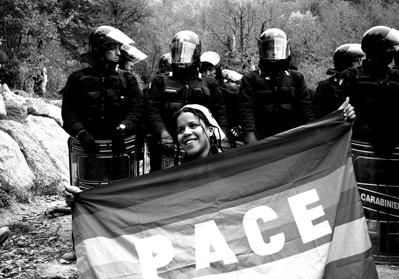 Woman with peace flag in front of police