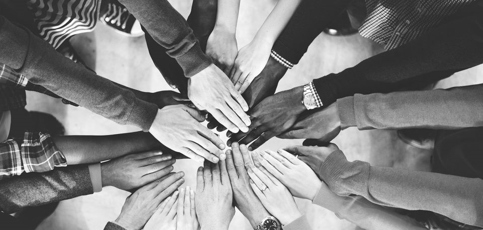 Black and white photo of hands meeting in a circle.