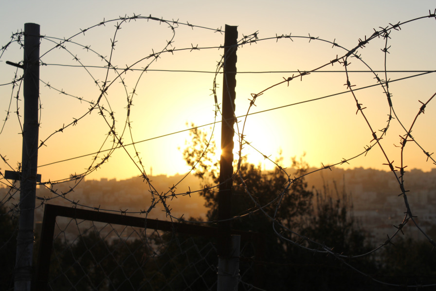 sunset through coils of barbed wire