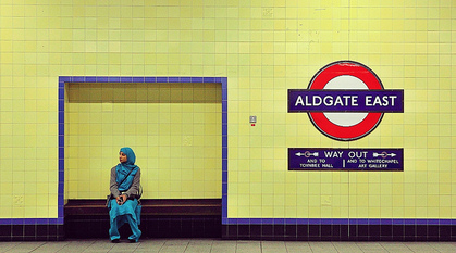 Woman sitting in Aldgate Tube station.