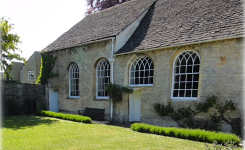 a stone building with large windows photographed from a summer garden.
