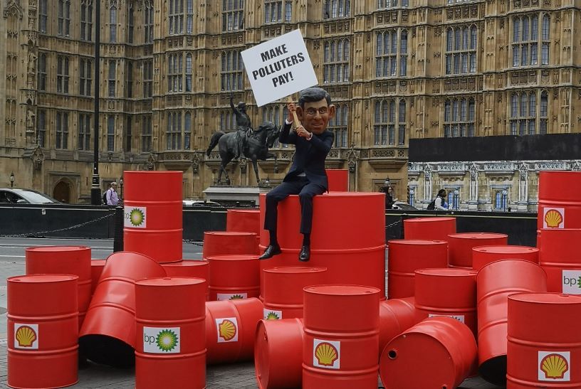 Man sitting on red oil barrels outside Parliament