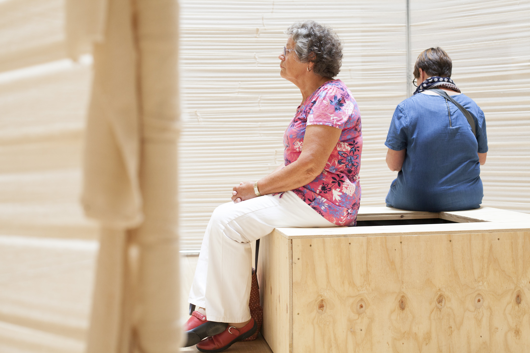 Two people listening inside a tent made of bandages 