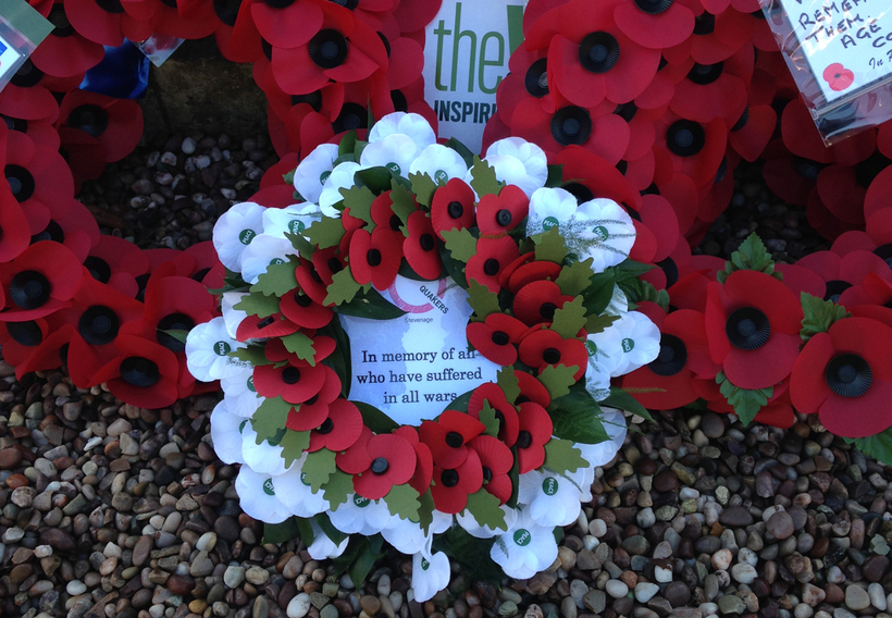 A wreath of red and white poppies stating "In memory of all who have suffered in all wars"