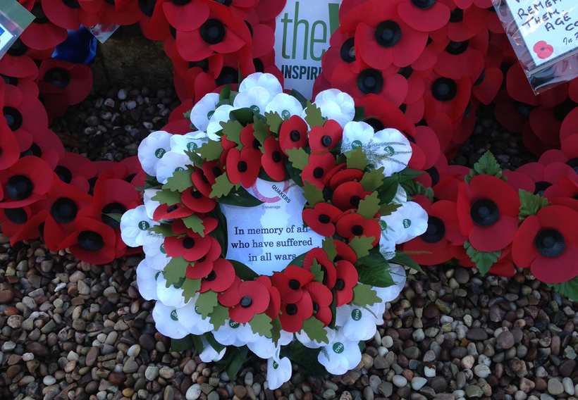 A wreath of red and white poppies stating "In memory of all who have suffered in all wars"