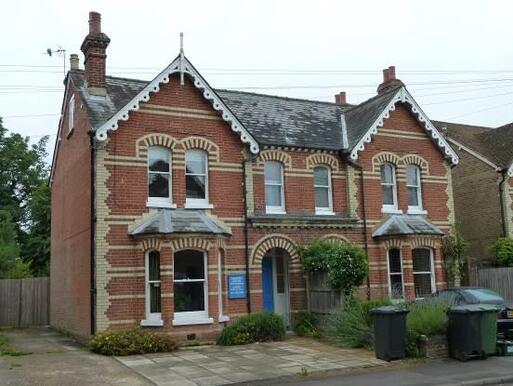 Semi - detached brick house with decorative brickwork and white bargeboards. 