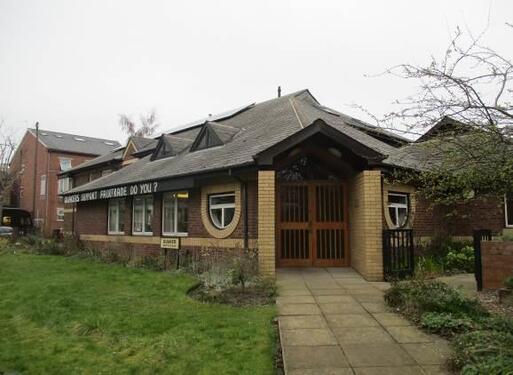 Short brick building with detailed semi-circular windows flanking central entrance slope. 