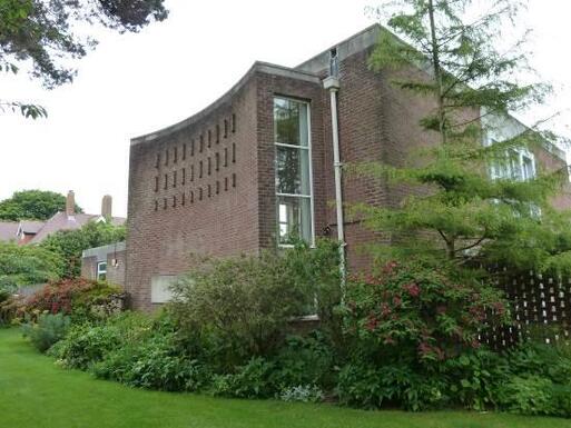 Tall brick building with sweeping concave wall on its left side decorated with extruding brick patterns. 