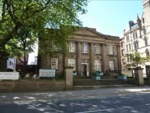 Large building with four full height decorative columns to the front, the building is accessed by wide stone steps. 