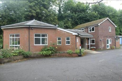 An octagonal brick meeting room is attached to a house via a small porch entryway. 