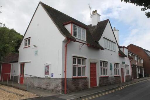 On-street white townhouse with large windows and red decorative detailing.