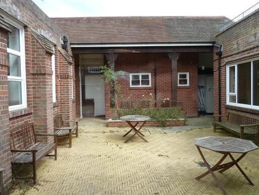 Interior redbrick courtyard with tables, chairs, and benches within its space. 