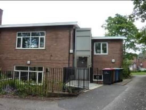 Brick building with wide windows and large grey entrance extension.