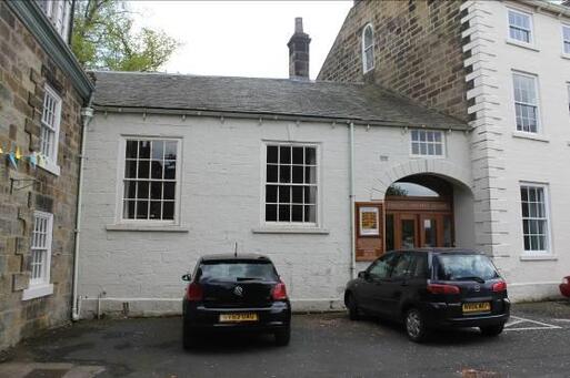 One storey white terraced building with two large windows and wooden entrance doors.