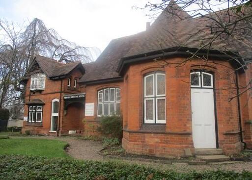 Very large brick house with black and white window frame detailing, 'Friends Meeting House' archway over the front entrance.