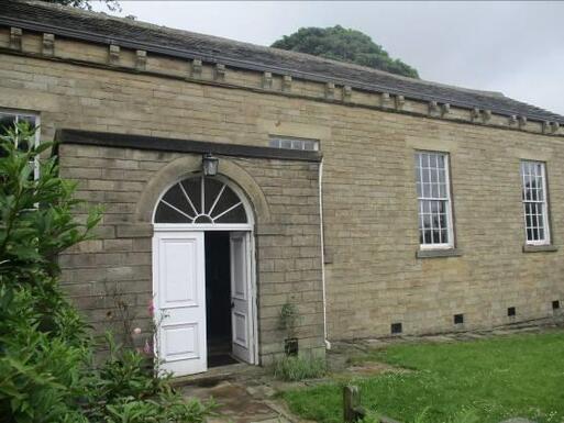 Short stone building with large windows and white entrance doors. 