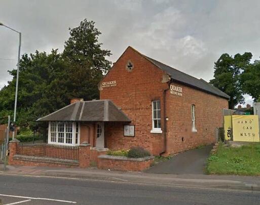 One-storey brick building with tall feature windows is flanked on both sides with 'Quaker Meeting House' lettering.