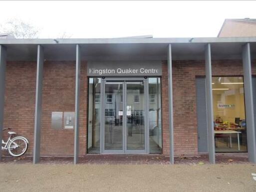 Brick building with grey pillars and glass double door entrance, above which reads 'Kingston Quaker Centre' 