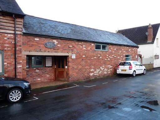 Undistinguished but humble low ground floor building with brown doors.