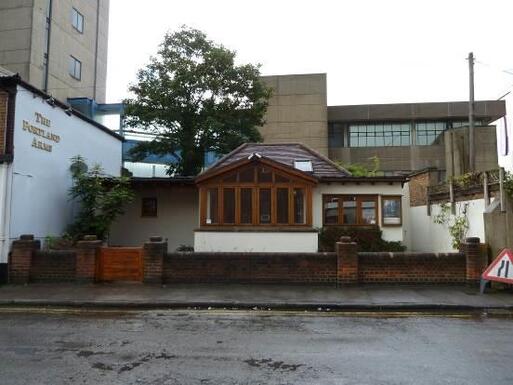 White small inter-war house with extension and burial area.