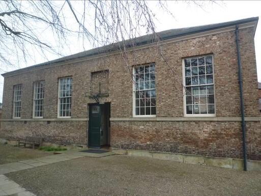 Large brick meeting house with massive windows and walled burial ground on premises.