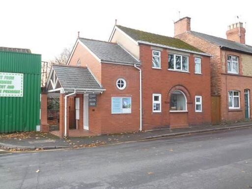 Red brick built simple house with conspicuous roof which in every part is lower than previous.