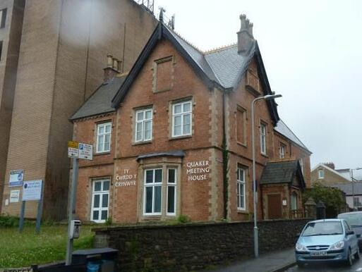 Brick laid building with sign 'Quakers Meeting House' and  original entrance with the datestone.