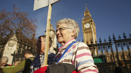 Two standing outside Westminster, holding a sign about climate justice