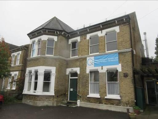 Grey brick house with large Quaker banner hanging underneath two large front facing windows. 