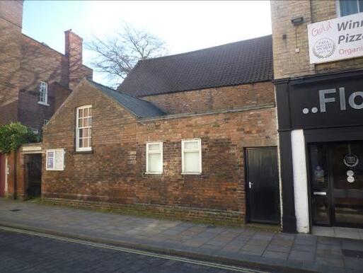 Brick building with small windows faces onto the street.