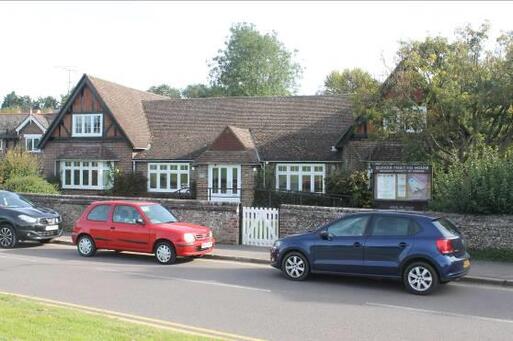 Large brick house with double-fronted bay windows and a large garden. Quaker Meeting House noticeboard to front. 