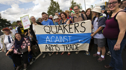 A group of Quakers standing and sitting around a banner with the words 'Quakers Against the Arms Trade' on it.