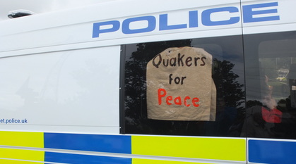 A Quakers for Peace sign in the window of a police van, held up by Quakers arrested inside