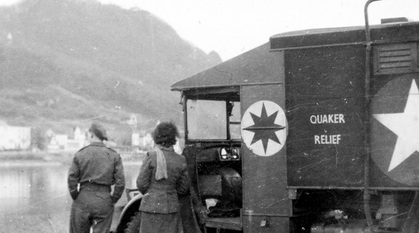 A black and white photograph of a man and woman by a Quaker Relief van 
