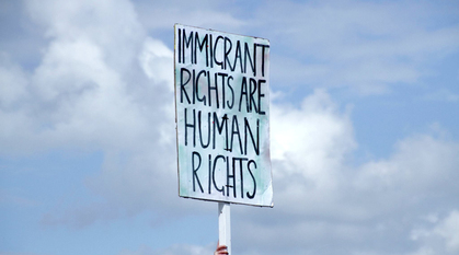 A demonstration holds a placard which reads 'immigrant rights are human rights'