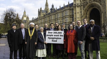 A group of faith and charity representatives standing in front of Parliament with a sign saying over 300,000 people want the #gagginglaw fixed 