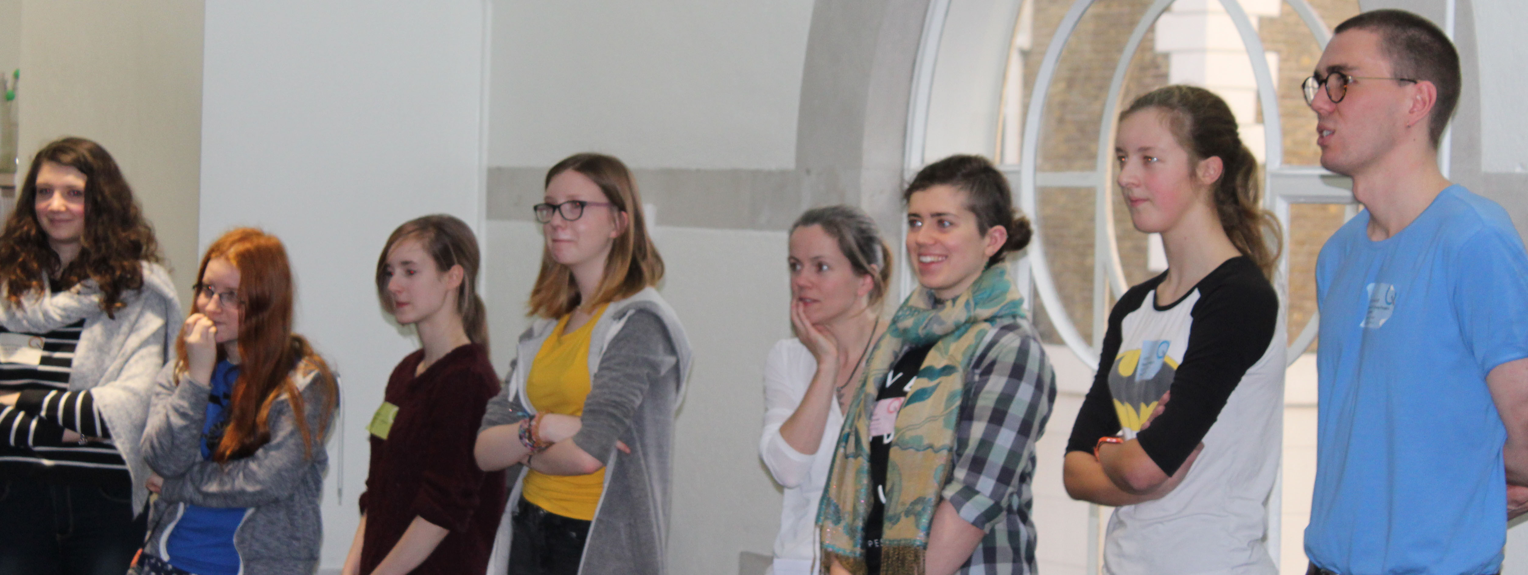 Young people standing in a semi circle, listening in a session