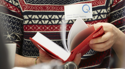 Young person wearing a woolly jumper flicking through red book 