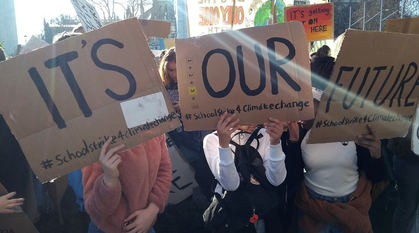 Three young people holding up placards saying 'It's our future' 