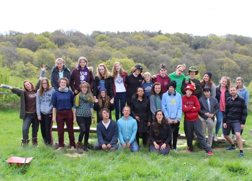  a group of young people and adults standing outside against trees