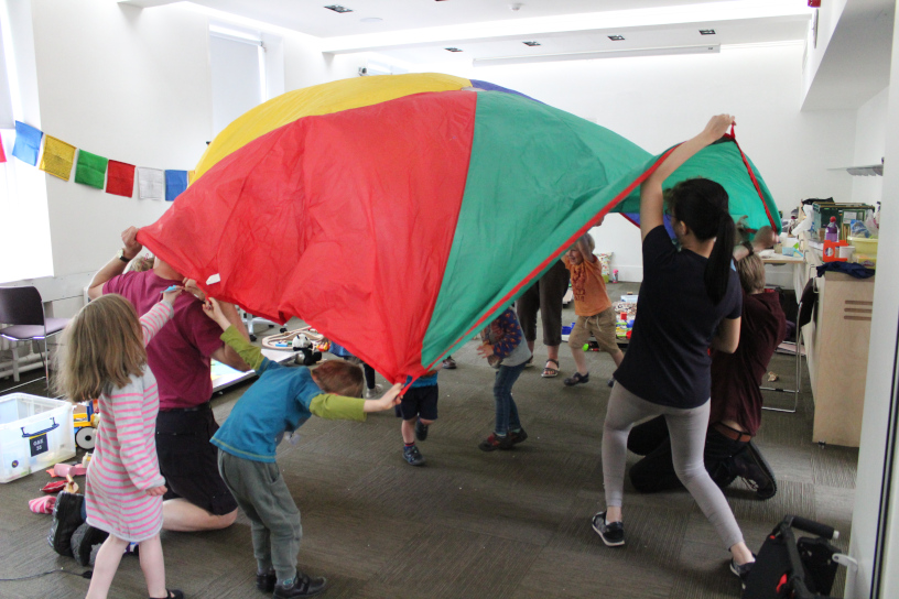 children in red/yellow/blue parachute