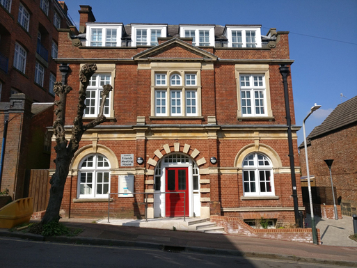 Red brick building with a red door and large windows.
