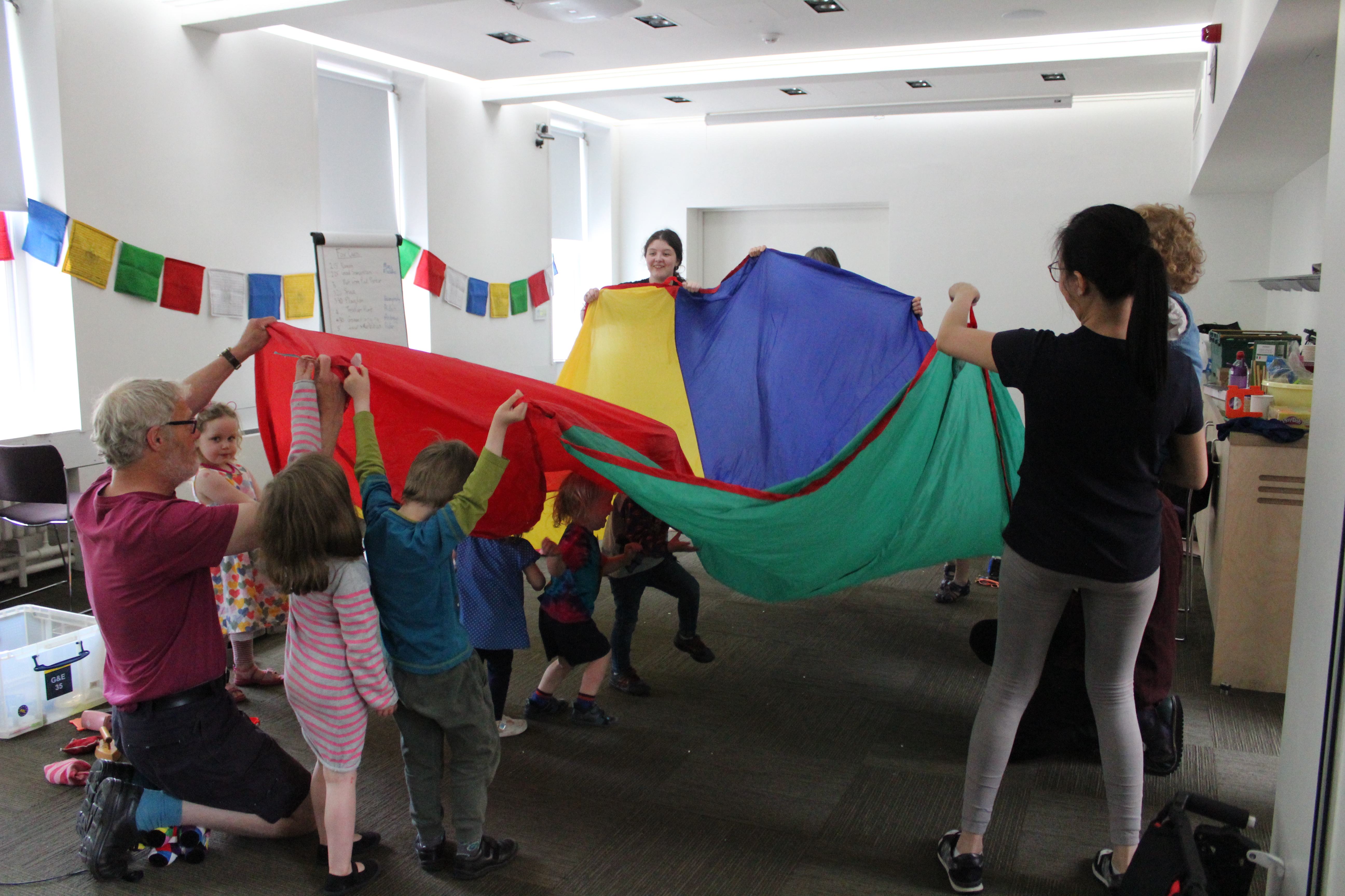 photo showing group of children aged 3-7 playing with a parachute 