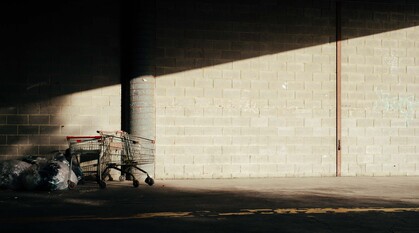 two abandoned shopping trolleys next to several rubbish bags 