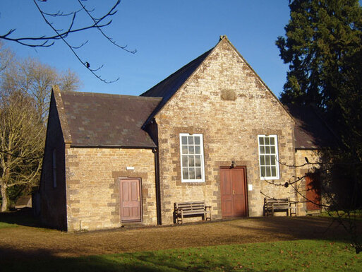 Stone, single-storey building with three brown doors.