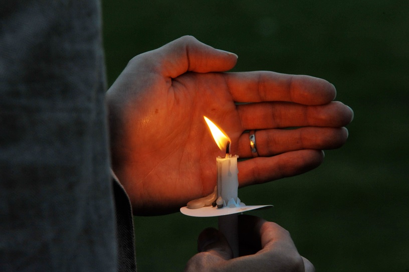 hand cradles lit candle