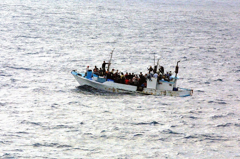 overcrowded small boat in expanse of sea